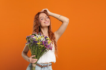 Poster - Beautiful young hippie woman with bouquet of colorful flowers on orange background, space for text