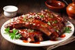 A plate of barbecue ribs sits on a white plate. The ribs are cooked to perfection and the barbecue sauce is rich and flavorful. The ribs are tender and juicy, and the meat falls off the bone easily.