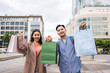 Portrait of Asian couple shopping goods outdoors in department store.