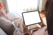 © Farknot Architect - Mockup image of a woman holding digital tablet with blank desktop screen while sitting on a sofa at home