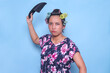 Angry Asian woman with hair curlers on head raise hand about to slap with sandal