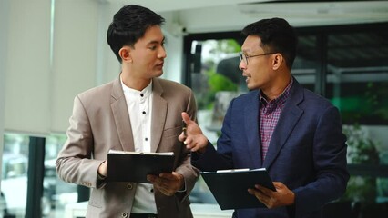 Wall Mural - Two professionals smiling, discussing over model houses on a table, possibly planning or reviewing a housing project on large land. Asian people, only businessman, Middle-age