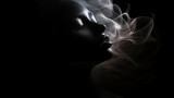 Fototapeta  - weibliches Beauty Model in sinnlicher Pose mit Nebel/ Rauch und Lichteffekten. Low Key Portrait bei dramatischem Licht. Querformat 16:9 Format. Generative Ai.