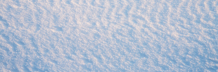 Wall Mural - Beautiful winter background with snowy ground. Natural snow texture. Wind sculpted patterns on snow surface. Wide panoramic texture for background and design.