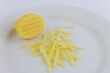 A miniature grater and grated potatoes on a white plate.