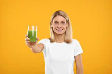 Poster - Happy woman with glass of fresh celery juice on orange background