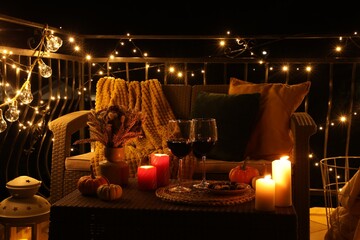 Wall Mural - Glasses of wine, burning candles and autumn decor on outdoor terrace in evening