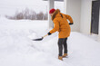 Man is clearing the snow near house and on staircases hovelling at the winter season. Winter storm and season specific