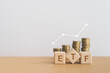 ETF abbreviation for Exchange Traded Fund written on wooden cube blocks with blurred stack of coins and white increasing graph line. Copy space included