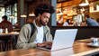 © Alfonso Soler - Young man working on laptop, boy freelancer or student with computer in cafe at table.