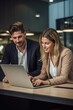 © Stock 4 You - Vertical shot of diverse partners mature Latin businessman and European businesswoman discussing project on laptop at table in office. Two colleagues of professional business people working together.