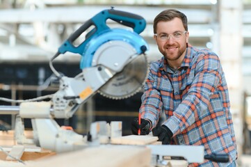 Wall Mural - Wood cutting table with electric circular saw. Professional carpenter in uniform cutting wooden board at sawmill carpentry manufacturing . Sawing machine