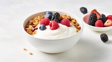 A Bowl Of Greek Yogurt Topped With Granola, Mixed Berries, And A Drizzle Of Honey