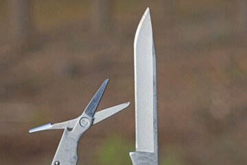 two tools from a white knife blade and a small scissors on a brown background