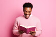 Cute African American young man toothy smile hold read opened book isolated on pink color background