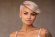 © AI_images - Young Latin pretty smiling model with short blonde hair, beautiful face healthy skin and tattoos looking at camera isolated at beige background.
