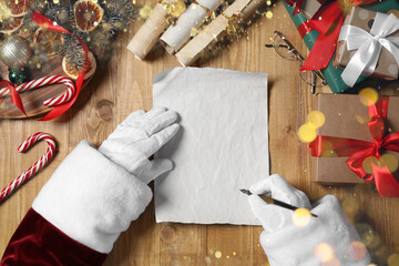 Wall Mural - Santa Claus writing letter with fountain pen at wooden table, top view. Space for text