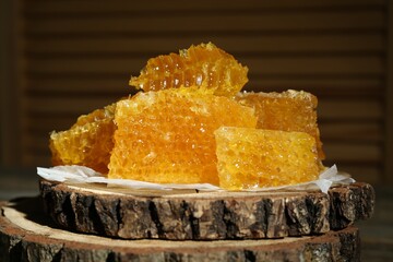 Wall Mural - Natural honeycombs on stump against blurred background, closeup