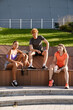 © Drobot Dean - Group of three fitness people smiling at camera while sitting outdoors