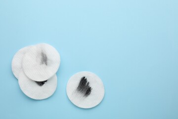 Wall Mural - Dirty cotton pads after removing makeup on light blue background, flat lay. Space for text