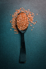 Wall Mural - Wooden spoon with flax seeds, on a dark background. Organic food, superfood. Top view.