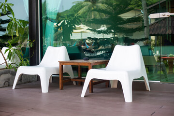 Two white chairs and a table near the glass window of a cafe. Holidays in tropical Asia