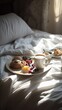 © Ilia - Tray with breakfast food on the bed inside a bedroom in morning light. Coffee, tea, fresh juice and croissants with berries and fruits.