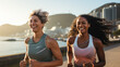 Two women jogging by the sea with urban skyline.