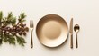  a place setting with a gold plate, silverware, and pine cones on a white background with a pine branch and pine cones on the side of the plate.