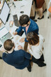 © qunica.com - Business professionals collaborating in a creative office, working late into the night to meet a project deadline. Together, they analyze reports and plan for financial growth and profitability.