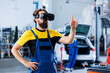 Focused technician in car service uses virtual reality to visualize automobile components in order to repair them. Garage expert wearing high tech vr headset while fixing vehicle issues