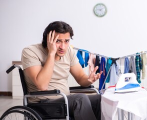 Wall Mural - Young man in wheel-chair doing ironing at home