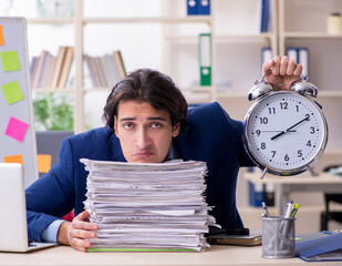 Wall Mural - Young male employee unhappy with excessive work