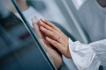 the romance of two couples' hands pressed against the glass. The woman's hand is wearing a wedding ring and a white dress, while her partner's hand is wearing a black suit