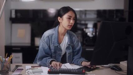 Asian female architect focuses on designing products. She utilizes a mouse and pen for precision, adding modern flair to the office. Her creations reflect a contemporary style.