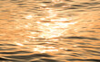 Blur dramatic image of capillary waves in the ocean. Soft focus of surface water river in warm tone. Reflection of sunset or sunrise ripples of water. Abstract background and copy space.