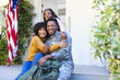 © WavebreakMediaMicro - Portrait of happy african american family embracing outside home with usa flag, copy space