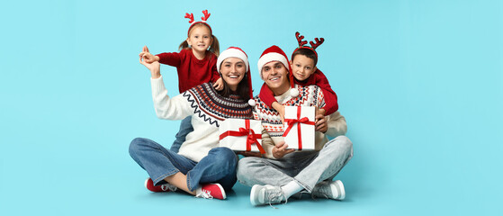 Wall Mural - Happy family in Christmas clothes and with gifts on light blue background