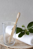 Fototapeta Sypialnia - Bamboo tooth brush in glass and towel on grey background