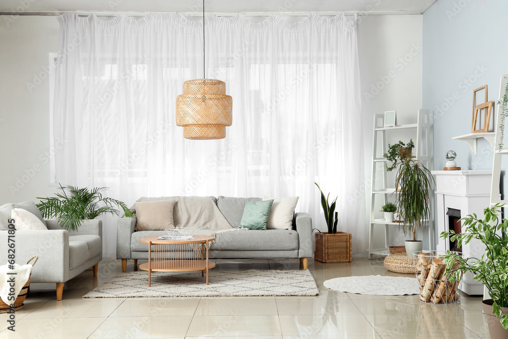 Interior of light living room with fireplace and grey sofas