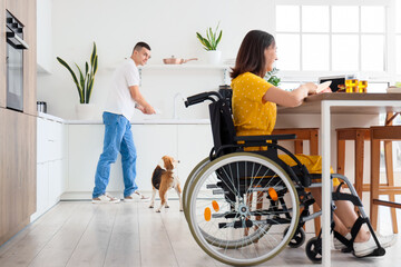 Canvas Print - Young man with Beagle dog and his wife in wheelchair at home