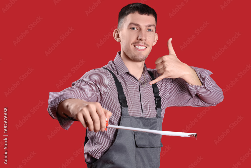 Male builder with tape measure showing "call me" gesture on red background