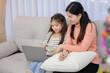 © เลิศลักษณ์ ทิพชัย - Asian mother and children or little girl enjoying holiday activities For education and learning that is fun and happy with using a laptop computer together in the living room at home