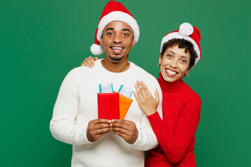 Wall Mural - Traveler fun couple man woman wear red casual clothes hold passport ticket isolated on plain green background. Tourist travel abroad in free spare time rest getaway. Air flight trip journey concept.