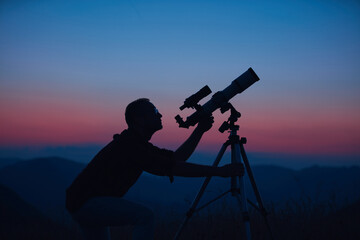 Wall Mural - astronomer looking at the night sky with a telescope.