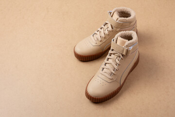 Pair of leather beige unisex sneakers on beige background