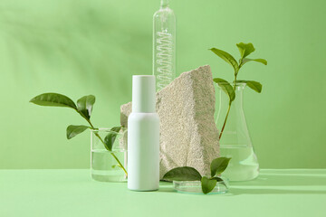 Wall Mural - Mockup scene for advertising cosmetic of natural extract - green tea. On green background, cosmetic bottle mockup displayed with fresh leaves and bud of green tea, stone and lab glassware. Front view