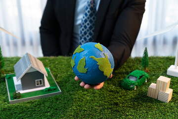 Eco business and save Earth concept shown by businessman or CEO holding paper globe in office with eco friendly mockup to promote CO2 and carbon footprint reduction for greener future. Quaint