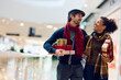 Happy multiracial couple buying Christmas present at mall.