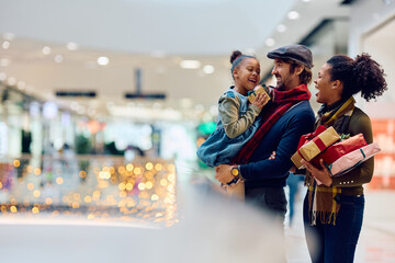 Cheerful multiracial family enjoys in Christmas shopping at mall.